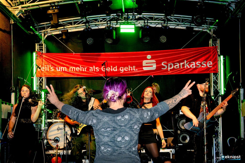 Musikband auf Bühne mit tanzendem Publikum
