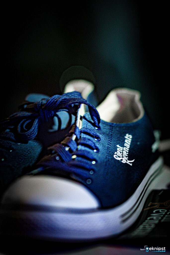 Blaue Turnschuhe mit Schnürsenkeln und Logo.
