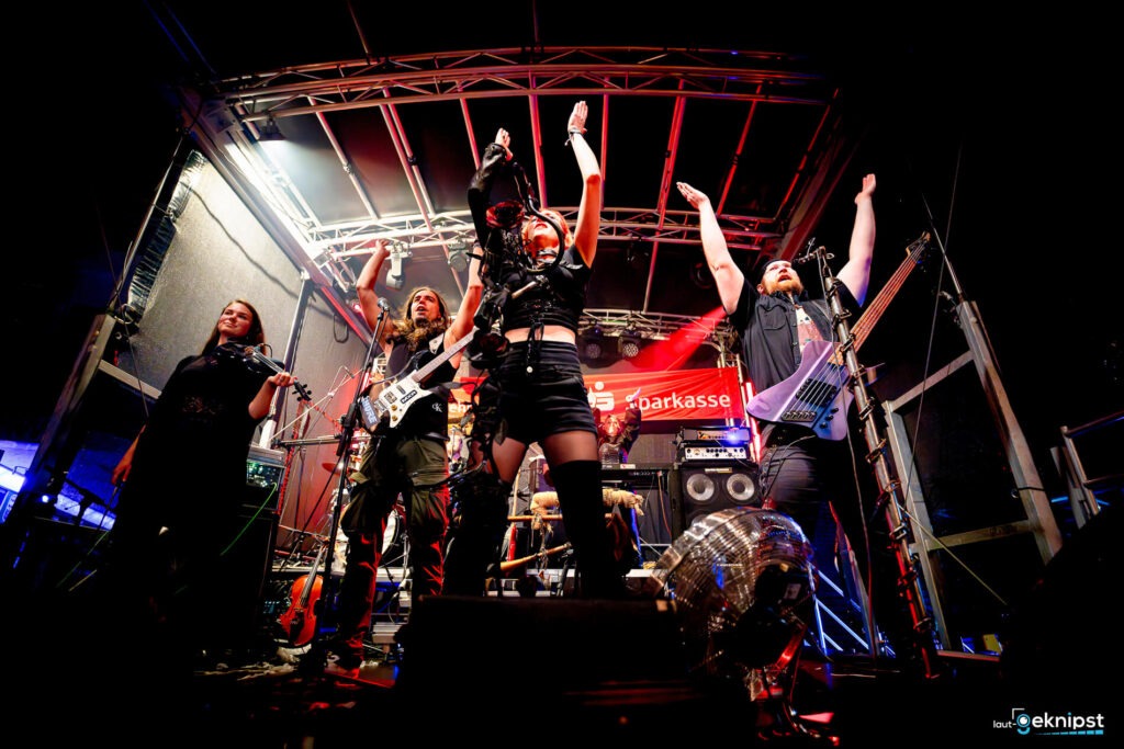Band spielt auf einer Bühne mit Lichteffekten.