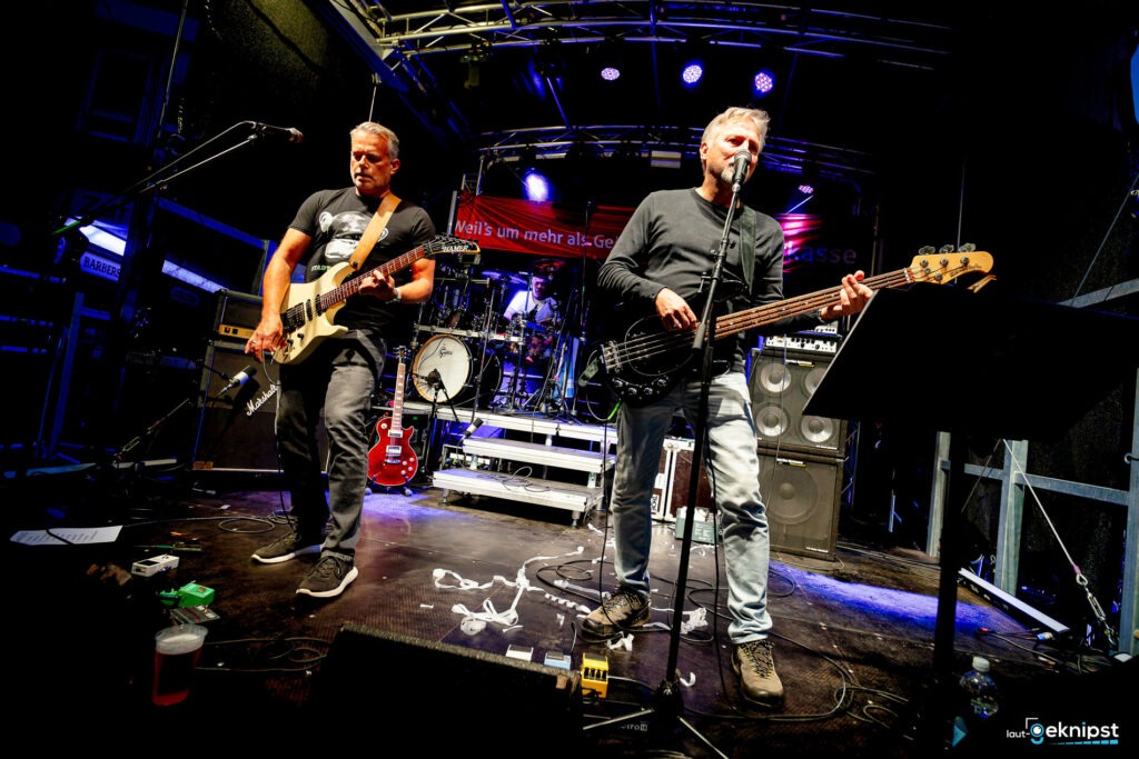Band spielt Live-Konzert auf Bühne mit Gitarren.