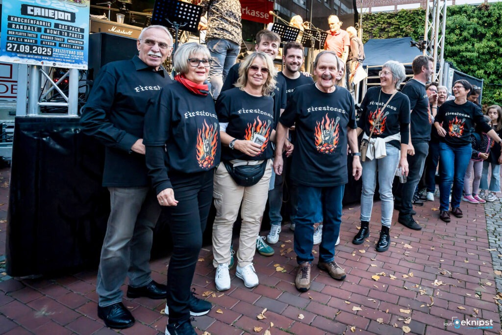 Gruppe in Firestones-Shirts vor Konzertbühne.