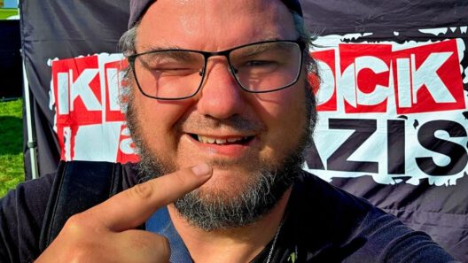 Person vor Plakat macht Selfie mit Fingerzeig.