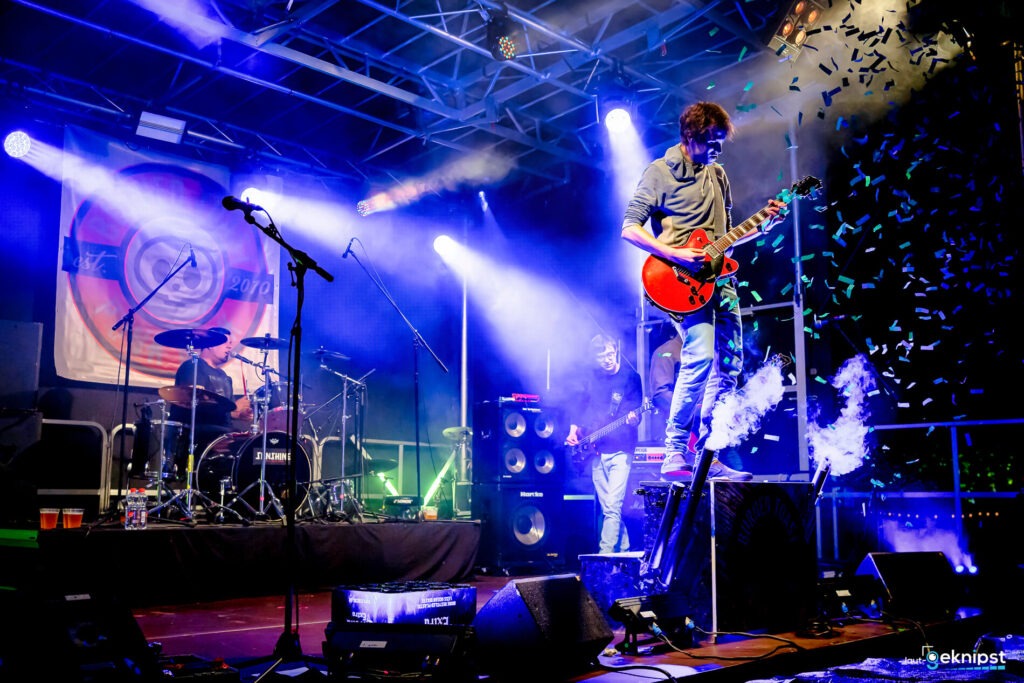 Live-Band spielt auf beleuchteter Bühne mit buntem Konfetti.