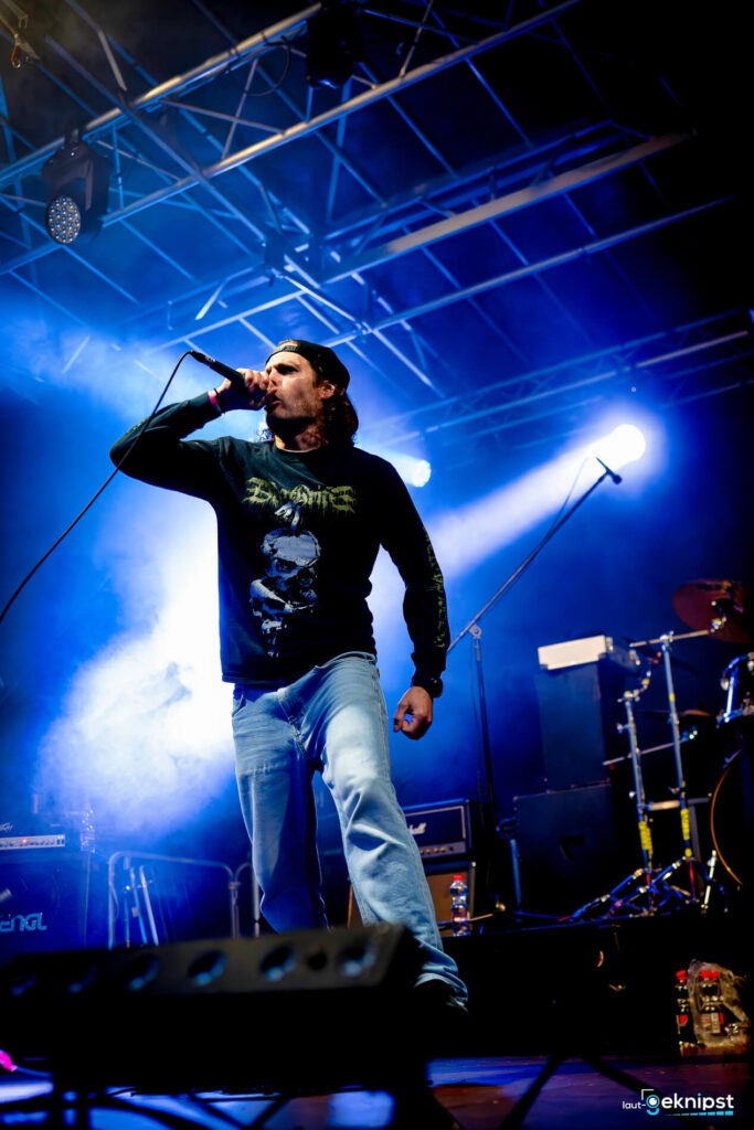 Sänger performt auf einer Rockkonzertbühne mit Mikrofon.