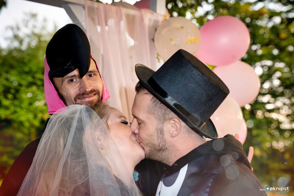 Hochzeitspaar küsst sich, background mit Kostümierter.