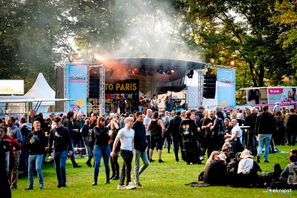 Freiluftkonzert mit Menschenmenge vor Bühne.