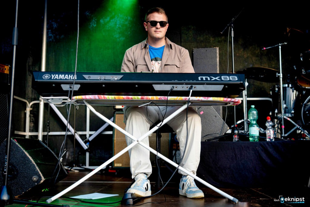Person spielt Keyboard auf der Bühne mit Sonnenbrille.