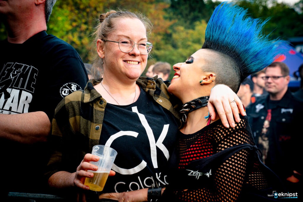 Zwei Menschen umarmen sich bei einem Festival.