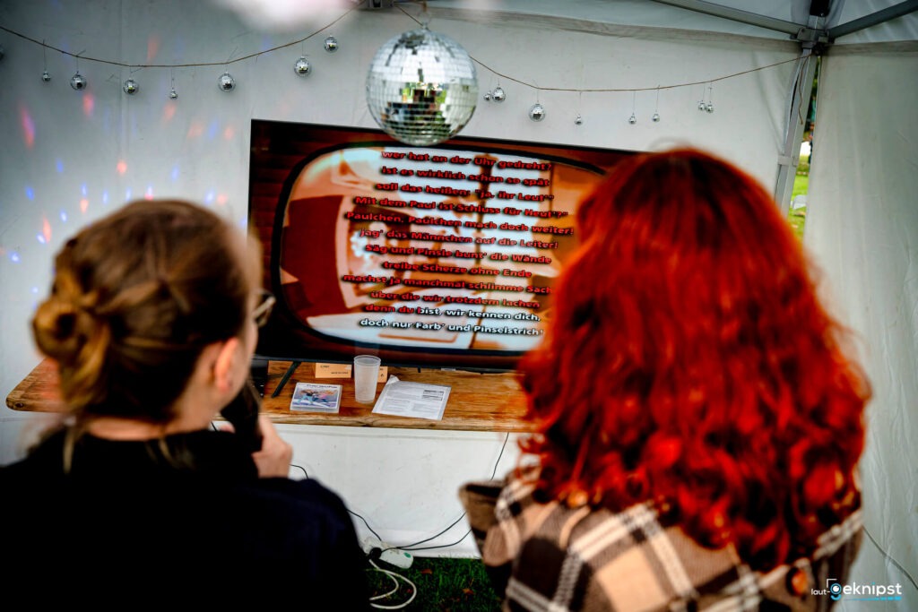Personen singen Karaoke vor einem Bildschirm.
