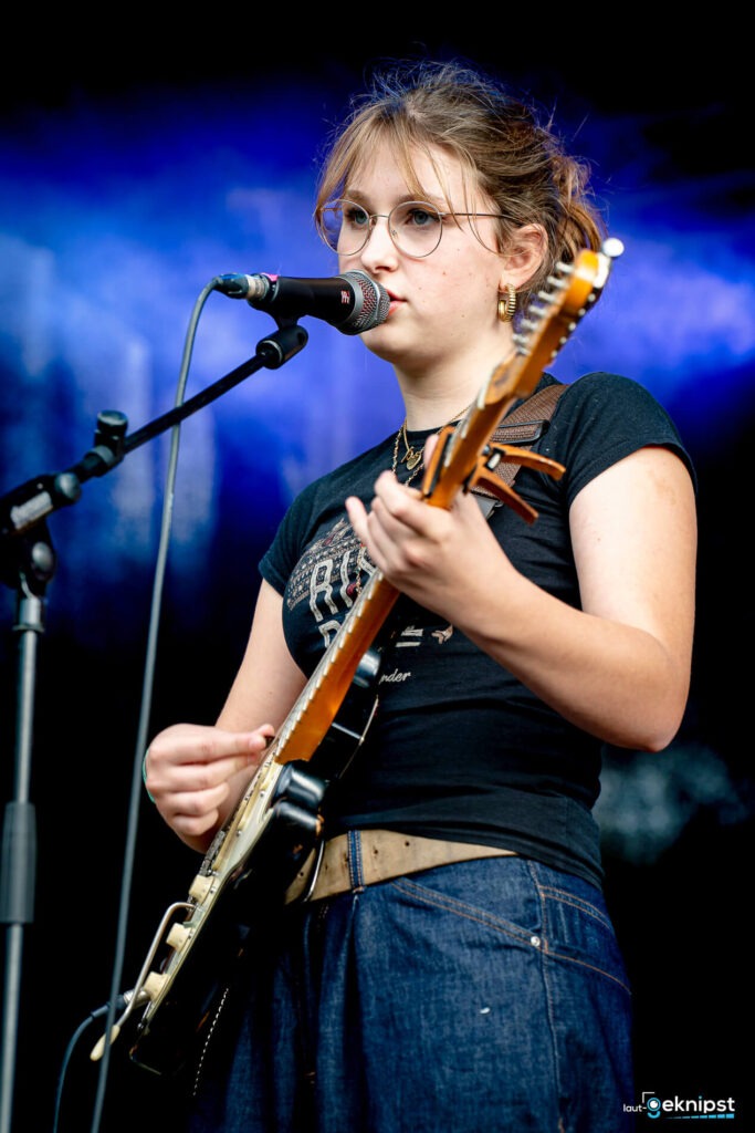 Frau spielt Gitarre und singt auf der Bühne.