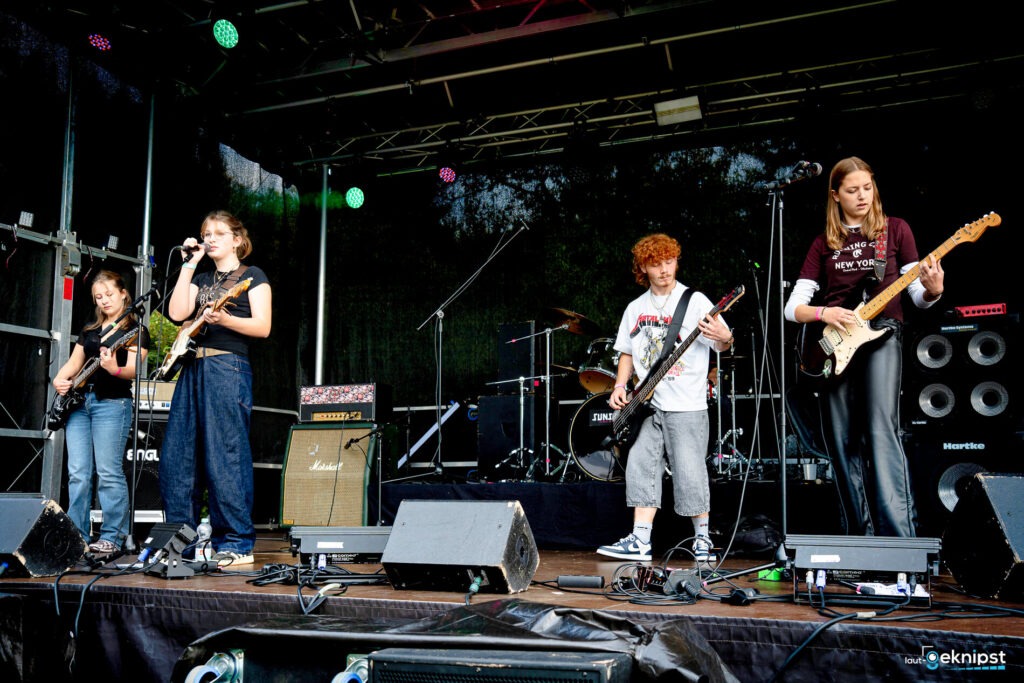 Band spielt auf einer Bühne mit Instrumenten.