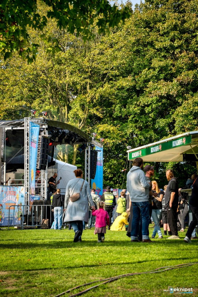 Open-Air-Konzert mit Bühne und Personen im Park.