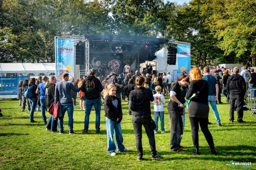Freiluftkonzert mit Menschenmenge vor der Bühne.