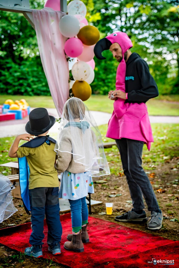 Kinder in Kostümen mit Flamingo-Person, bunte Luftballons