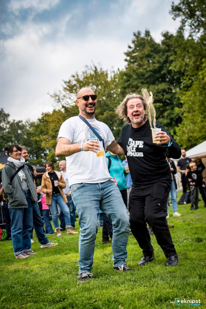 Zwei Männer tanzen fröhlich mit Bier.