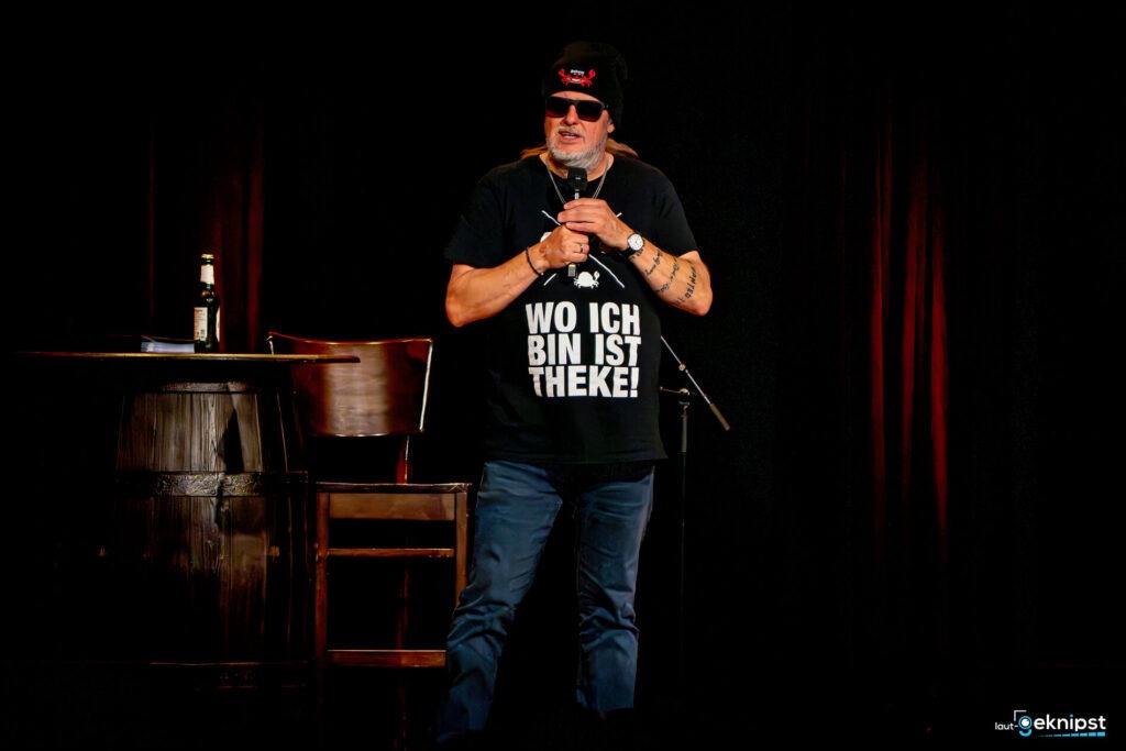Mann auf Bühne mit Theke-T-Shirt.