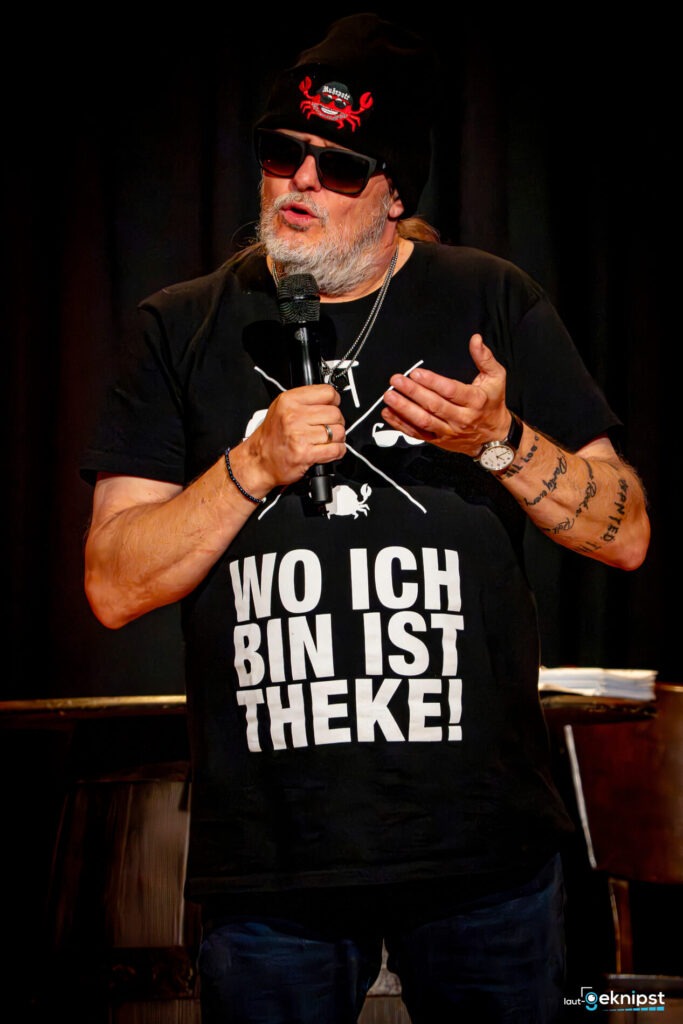 Person mit schwarzem T-Shirt und Mütze spricht.
