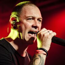 Mann singt auf roter beleuchteter Bühne