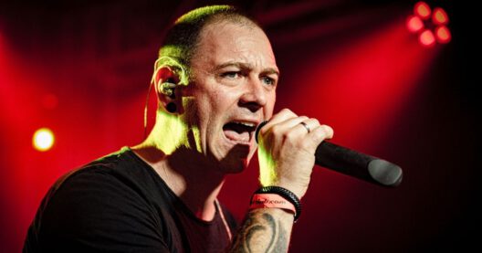 Mann singt auf roter beleuchteter Bühne