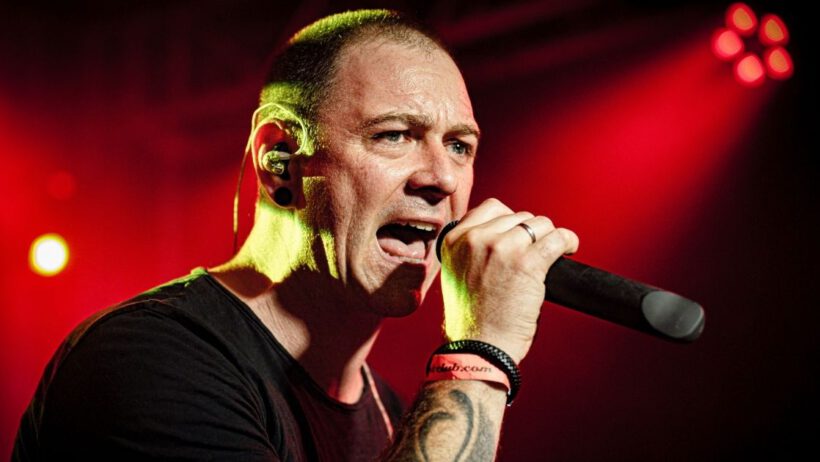 Mann singt auf roter beleuchteter Bühne