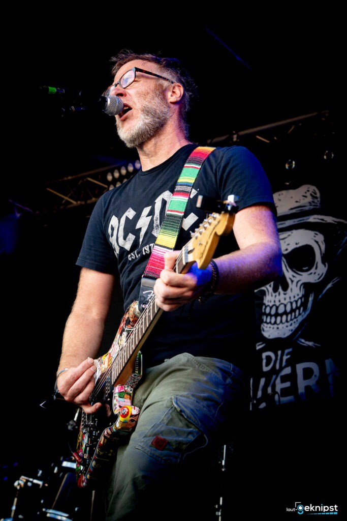 Gitarrist singt auf der Bühne mit Mikrofon