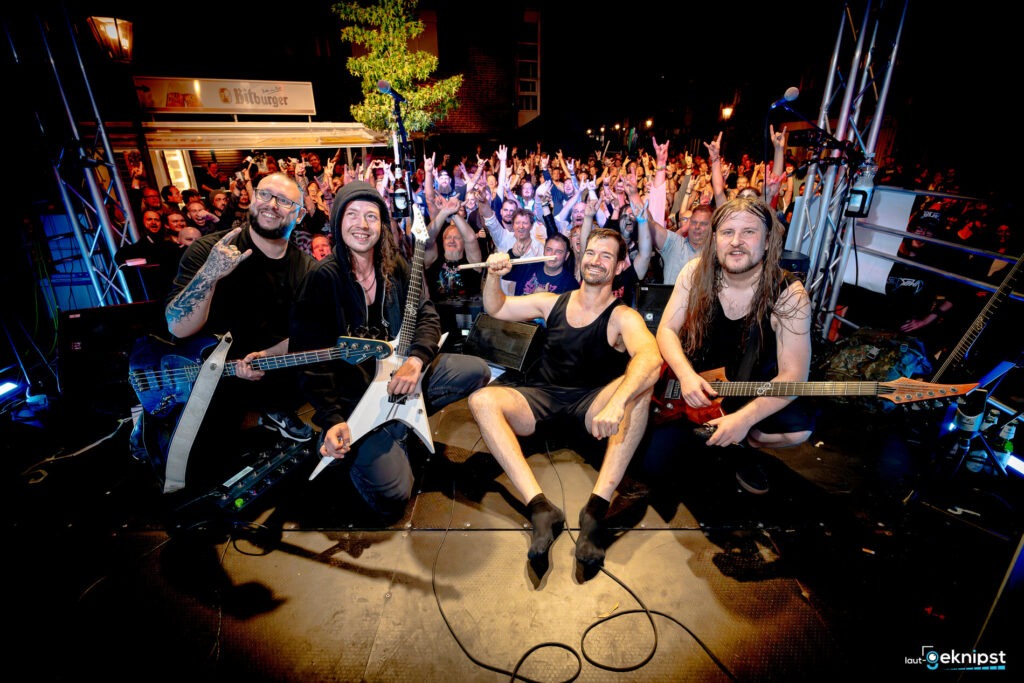Band pose mit Fans auf Bühne.