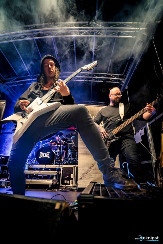 Musiker spielen Gitarre und Bass auf Bühne.