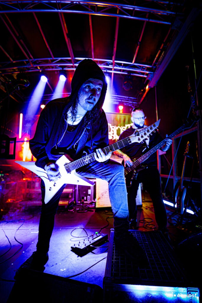 Zwei Rockmusiker spielen Gitarre auf einer Bühne.
