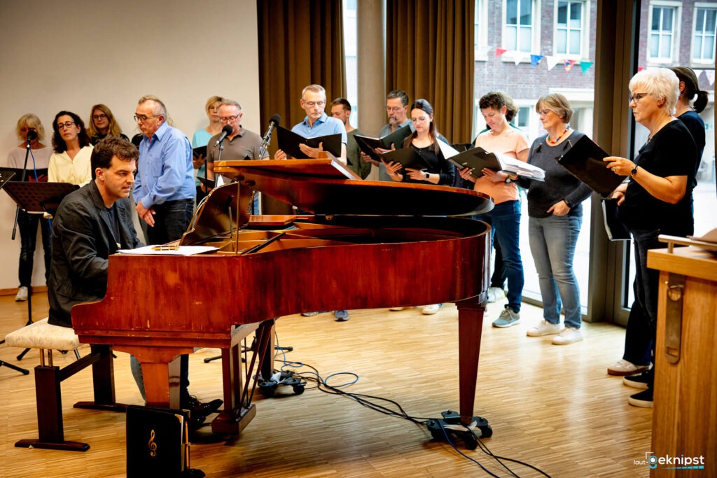 Chor singt neben Klavier im Proberaum.