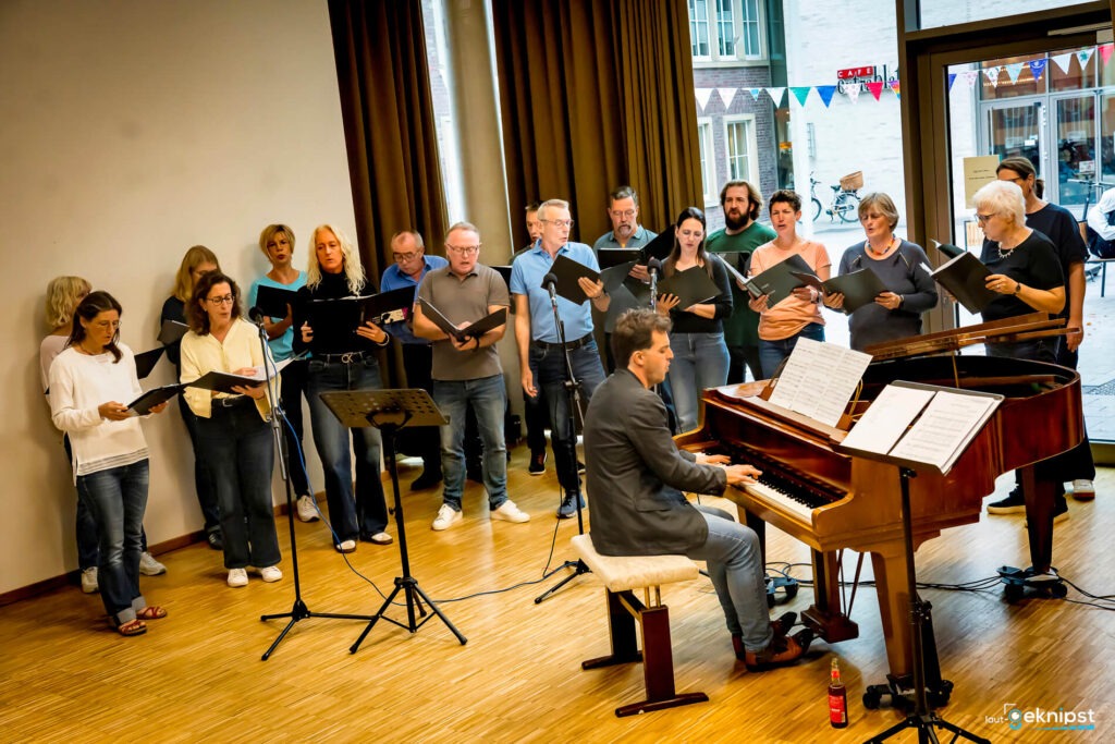 Chor singt mit Klavierbegleitung im Saal.