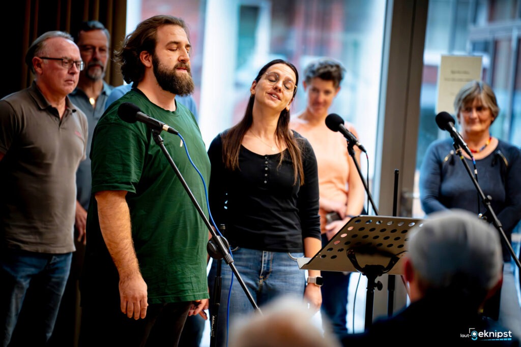 Menschen singen auf einer Bühne mit Mikrofonen.
