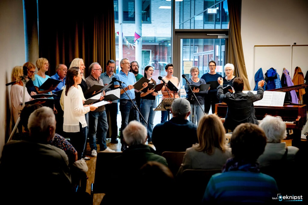 Chor singt vor Publikum in einem Raum.