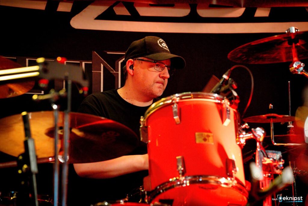 Schlagzeugspieler bei einem Konzert mit rotem Schlagzeug.