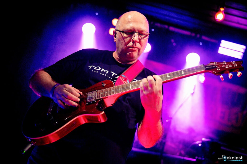 Musiker spielt E-Gitarre auf der Bühne.