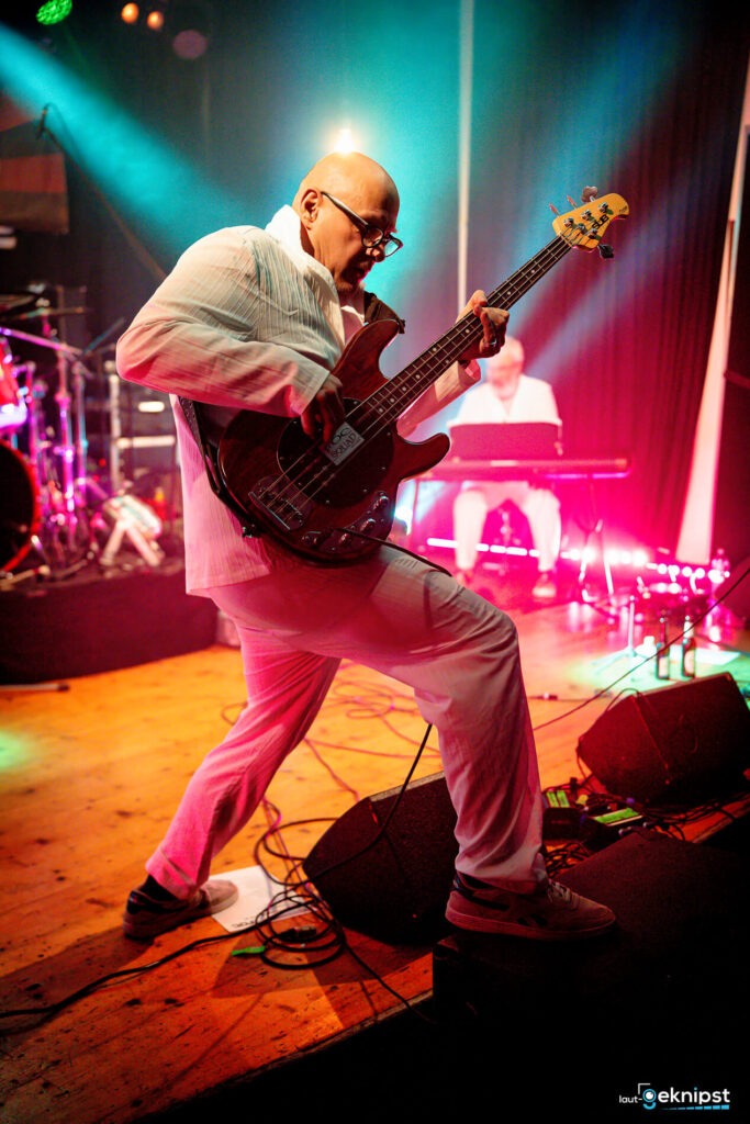 Bassspieler auf der Bühne in buntem Licht.