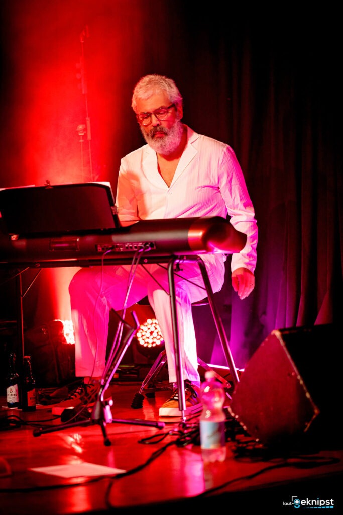 Mann spielt Piano in rotem Bühnenlicht
