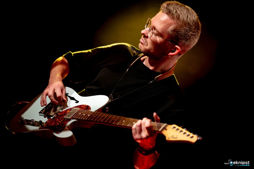 Mann spielt E-Gitarre auf der Bühne.