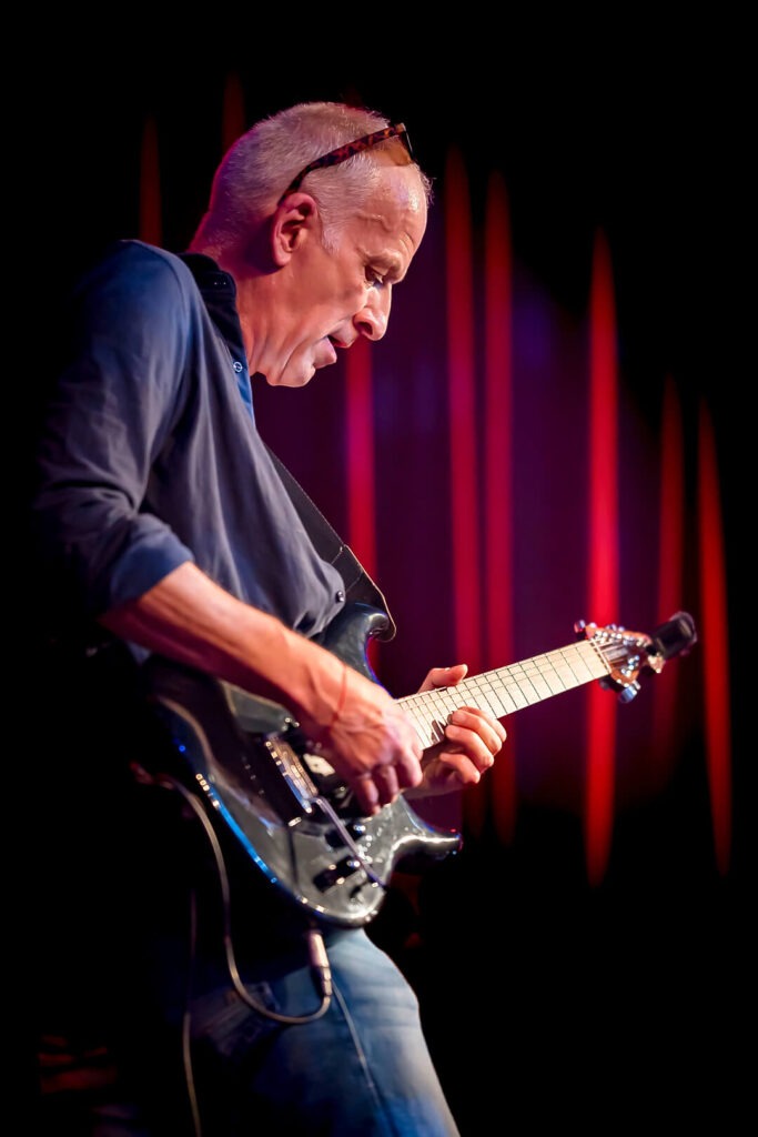 Mann spielt E-Gitarre auf der Bühne