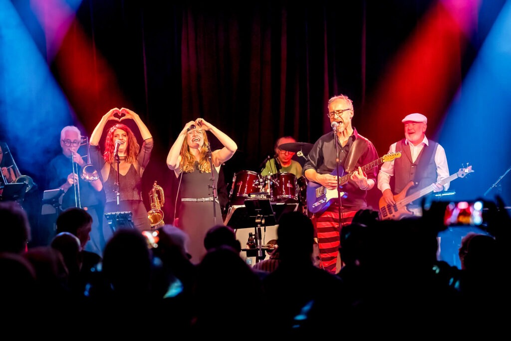 Band spielt live auf Bühne, buntes Licht