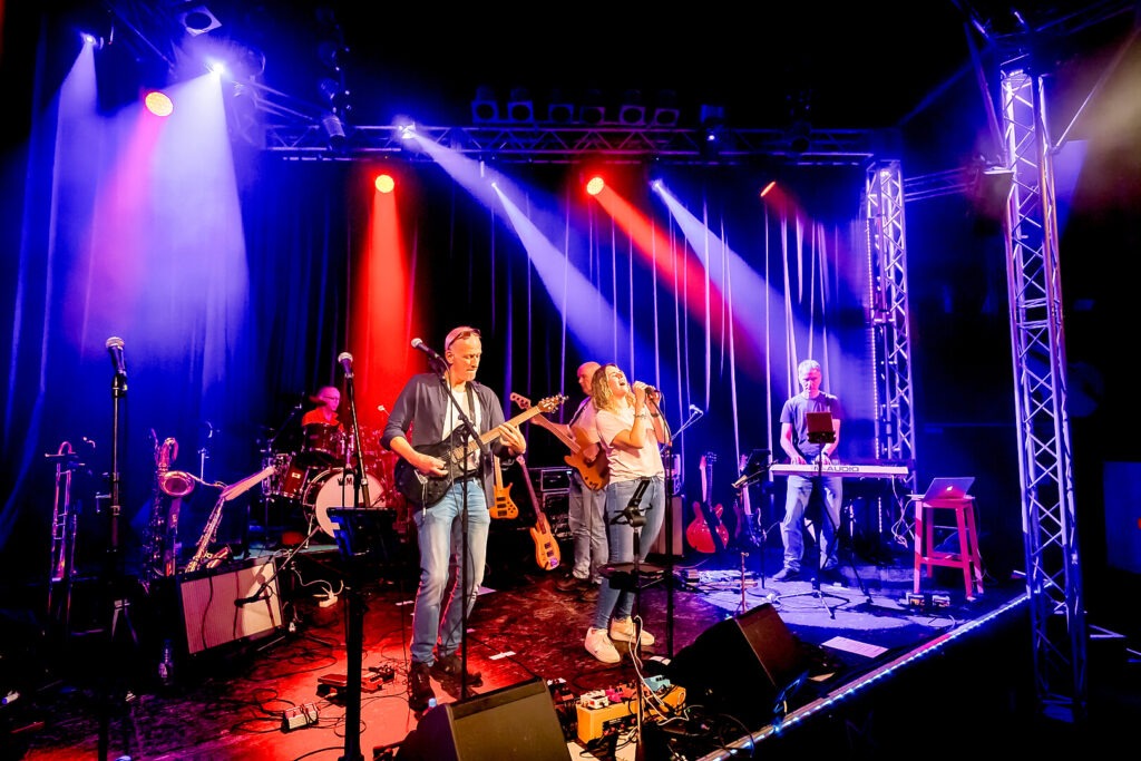 Band spielt Live-Konzert auf bunter Bühne.