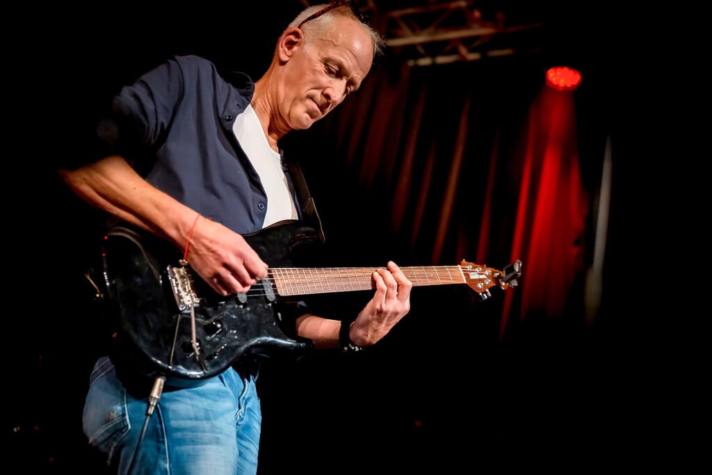 Mann spielt E-Gitarre auf Bühne
