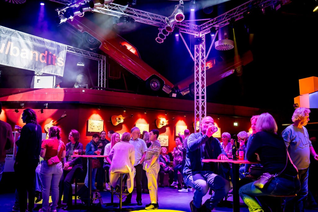 Menschen in einer bunten Bar mit Gitarren-Dekor.