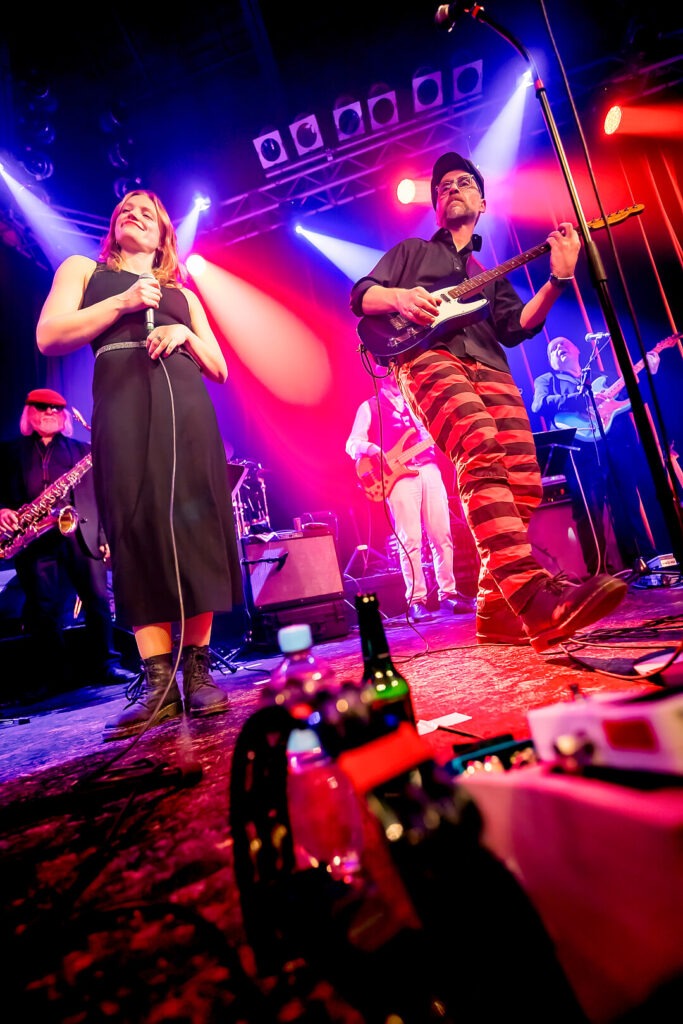 Band performt live auf einer farbenfrohen Bühne.