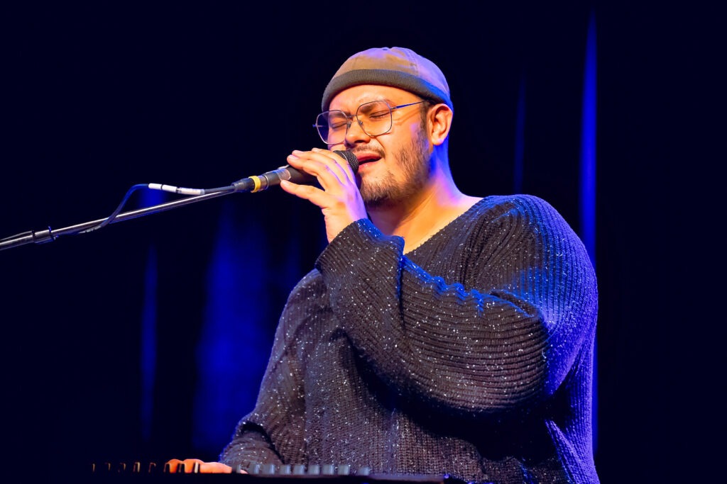 Person singt auf der Bühne mit Mikrofon.
