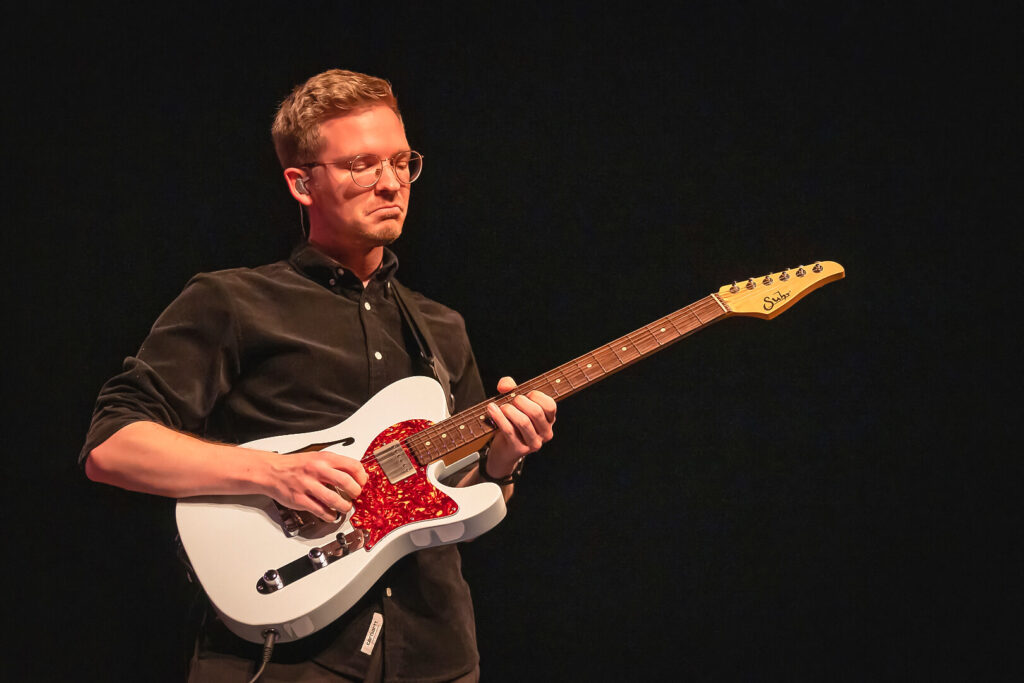 Mann spielt E-Gitarre auf der Bühne