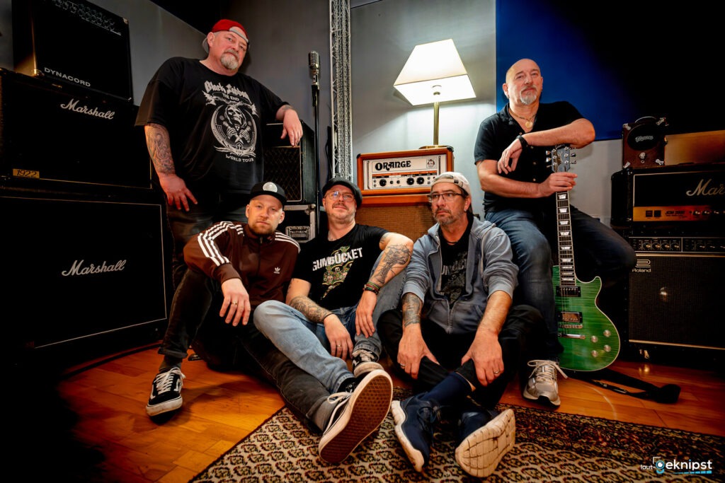 Bandmitglieder posieren im Musikstudio mit Verstärkern.