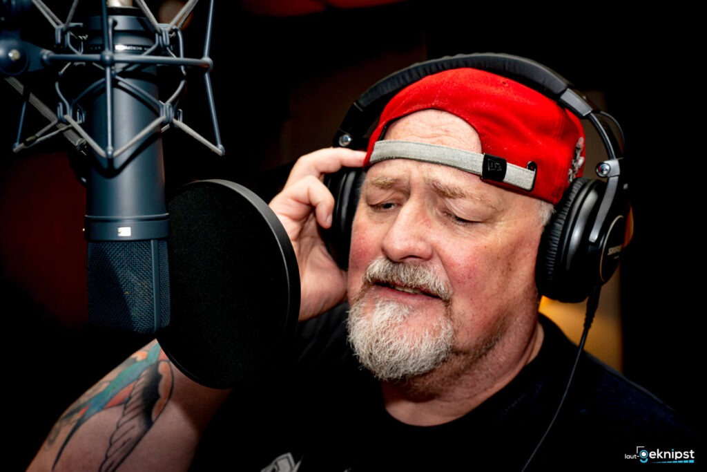 Mann singt im Aufnahmestudio mit Kopfhörern.