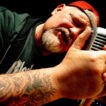 Mann singt in ein Mikrofon mit Tattoo.