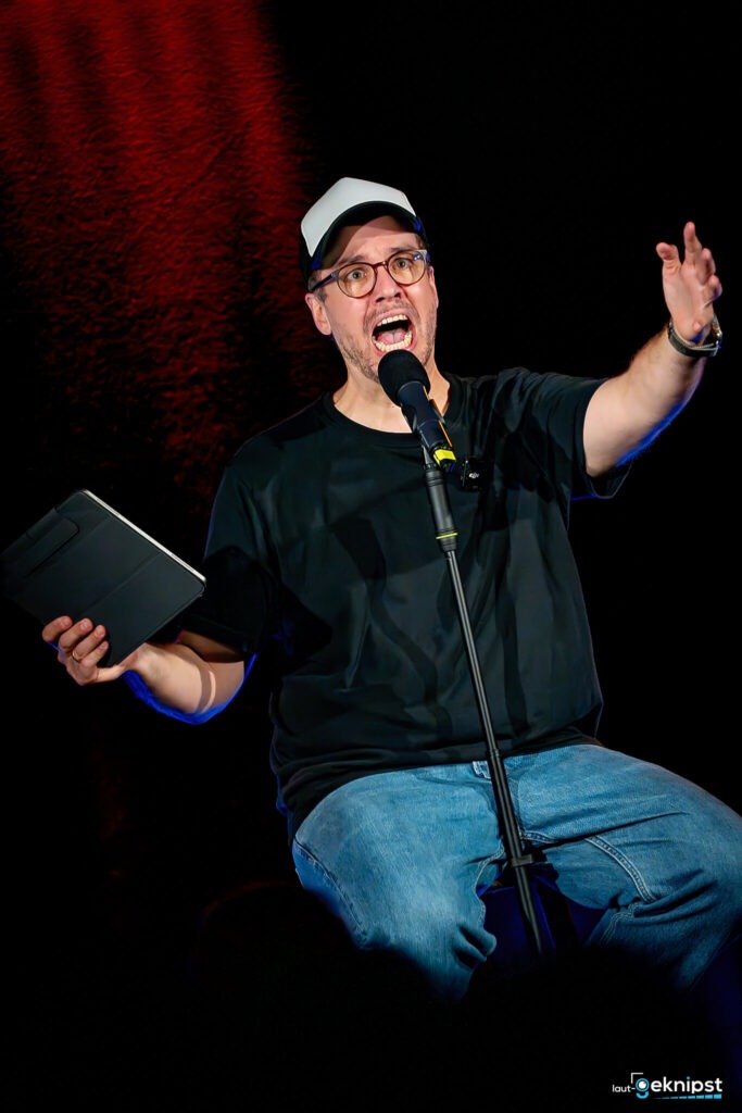 Mann spricht leidenschaftlich ins Mikrofon auf Bühne