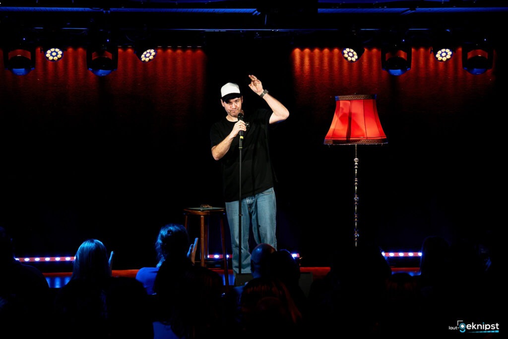 Comedian auf Bühne mit Mikrofon und Lampe